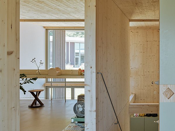 Foto, Innenraum eines modernen Wohngebäudes mit hellen Holzoberflächen, Blick durch Flur in Wohnbereich mit Tisch und Fenster