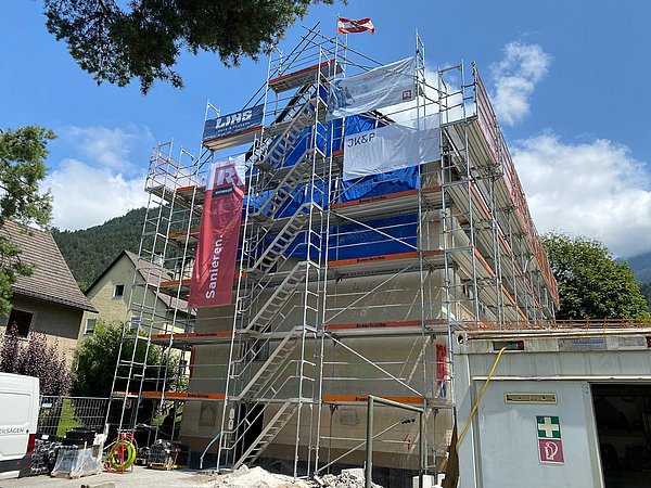 Foto, Mehrstöckiges Gebäude mit Gerüst und Bauplanen, Baustelle bei sonnigem Wetter mit blauem Himmel