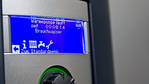 Foto, Display einer Wärmepumpe mit blauer Anzeige und Text zu Betriebszeit und Brauchwasser