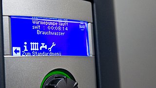 Foto, Display einer Wärmepumpe mit blauer Anzeige und Text zu Betriebszeit und Brauchwasser