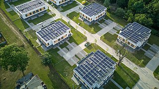 Foto, Luftaufnahme von mehreren modernen Wohngebäuden mit Flachdächern und Solarpaneelen in einer grünen Umgebung.