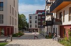 Foto, Innenhof zwischen modernen Mehrfamilienhäusern. In der Mitte läuft ein Kind hinter einem Ball.