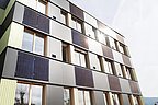 Foto, Mehrstöckiges Gebäude mit Fassadenverkleidung aus Solarpaneelen und Fenstern unter bewölktem Himmel