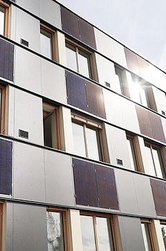 Foto, Mehrstöckiges Gebäude mit Fassadenverkleidung aus Solarpaneelen und Fenstern unter bewölktem Himmel