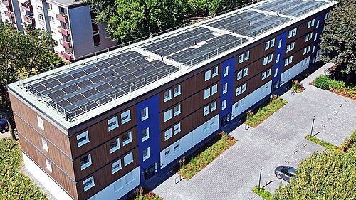 Foto, Vogelperspektive auf Mehrfamilienhaus mit Photovoltaik-Kollektoren auf dem Dach.