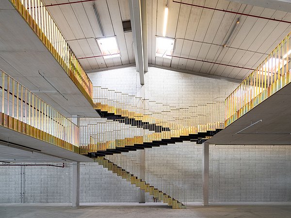 Foto, Offenes Treppenhaus mit gelben Geländern und Betonwänden in einem Industriegebäude