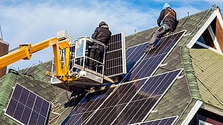 Foto, Handwerker montieren Solarpanele auf dem Dach eines Einfamilienhauses..