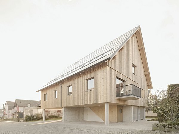 Foto, Modernes Holzhaus auf Stelzen mit Solarpaneelen auf dem Dach und kleinem Balkon