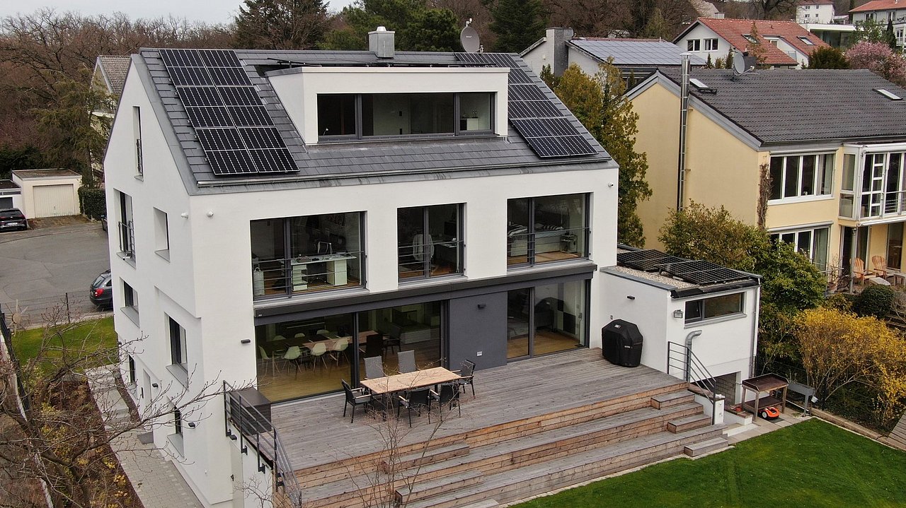 Foto, saniertes Einfamilienhaus mit geräumiger Terasse und Photovoltaikanalge auf dem Dach. 