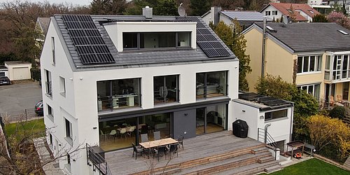 Foto, saniertes Einfamilienhaus mit geräumiger Terasse und Photovoltaikanalge auf dem Dach. 