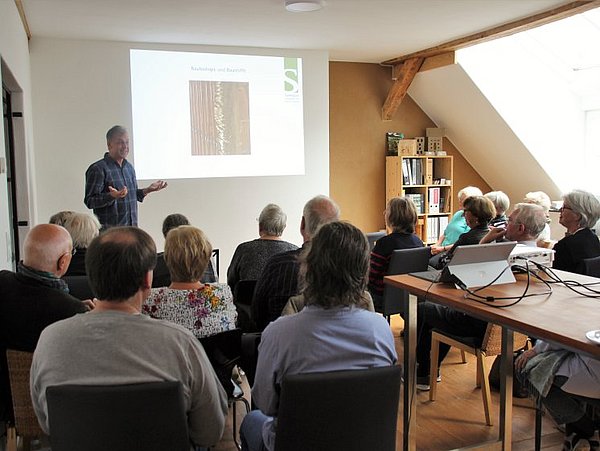 Foto, Schulung in einem hellen Raum mit mehreren Teilnehmenden, die einem Vortrag über Holzstrukturen folgen
