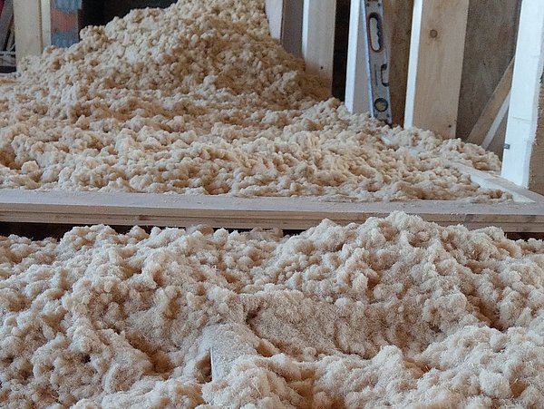 Foto, Große Menge Dämmwolle in einem Holzrahmen auf einem Boden in einem Rohbau