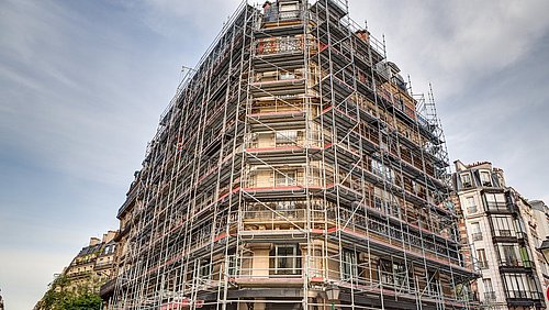 Foto, ein Mehrfamilienhaus ist eingerüstet und wird renoviert.