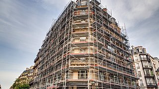 Foto, ein Mehrfamilienhaus ist eingerüstet und wird renoviert.