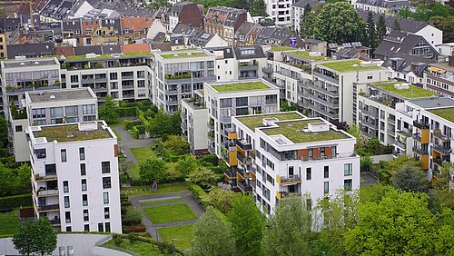 Foto, Moderne weiße Wohngebäude mit begrünten Dächern und umliegenden Bäumen in einer städtischen Wohngegend