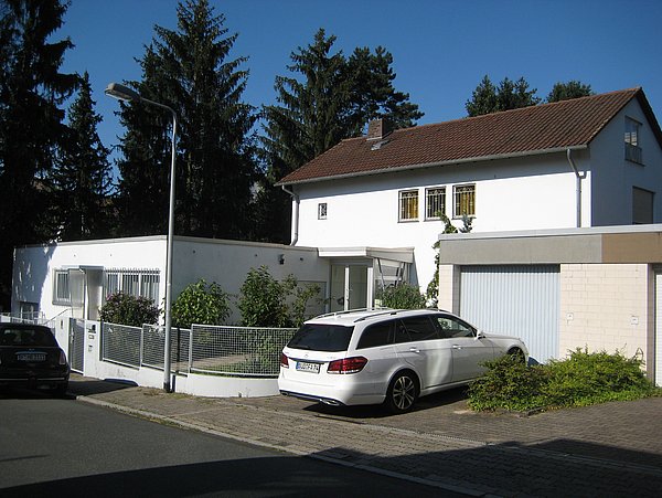 Foto, Straßenansicht eines Einfamilienhauses mit flachem Vorbau und Garagen vor der Sanierung