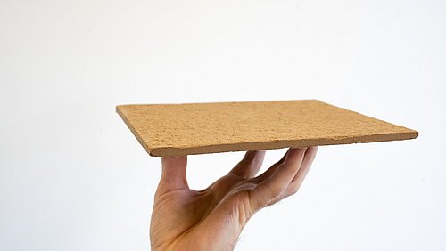 Foto, eine Hand hält eine Dämmplatte aus Lignin-Aerogel in die Höhe.