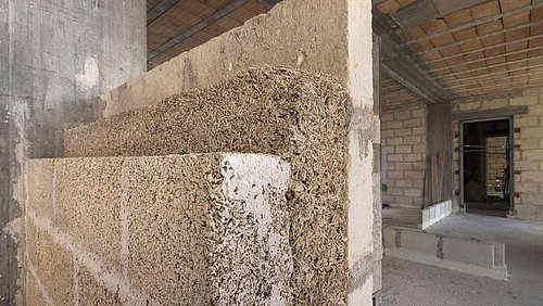 Foto, Ansicht einer Innenwand im Bauzustand, die aus verschiedenen Bauelementen mit Miscanthus (Chinaschilf) errichtet wird.