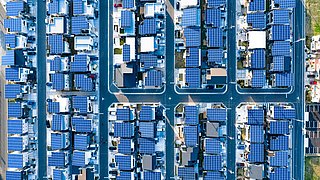 Foto, Luftaufnahme einer Siedlung, wobei auf jedem Dach eine Photovoltaikanlage platziert wurde.