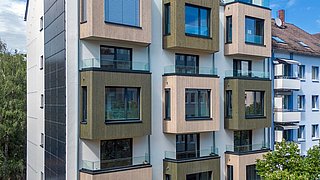 Foto, Außenansicht eines modern sanierte Mehrfamilienhauses mit Erkern, die mit Holz verkleidet sind