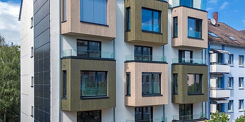 Foto, Außenansicht eines modern sanierte Mehrfamilienhauses mit Erkern, die mit Holz verkleidet sind