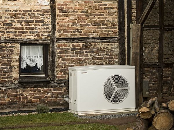 Foto, Teil eines Fachwerkgebäudes mit Photovoltaikanlage auf dem Dach und Außenanlage einer Wärmepumpe