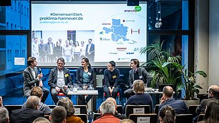 Foto, Podiumsdiskussion mit sechs Personen vor Publikum, im Hintergrund eine Präsentation mit Karte von Niedersachsen.