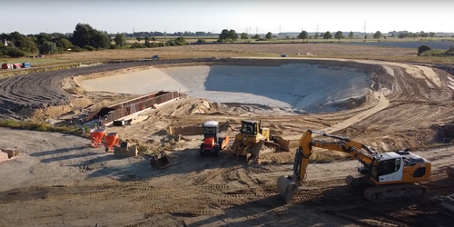 Foto, Große Baugrube mit Baggern und Baumaschinen in ländlicher Umgebung bei Meldorf