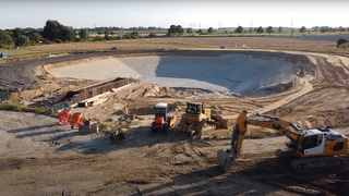 Foto, Große Baugrube mit Baggern und Baumaschinen in ländlicher Umgebung bei Meldorf