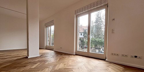 Foto, Leerer Wohnraum mit hellem Fischgrätparkett, großen Fenstertüren zum Garten und weißen Wänden