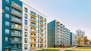 Foto, Blick auf die Fassaden mehrerer neu gebauter mehrstöckiger Wohngebäude vor blauem Himmel.