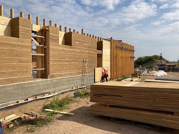 Foto, Baustelle eines Gebäudes in Lehmbauweise. Die Wände des Gebäudes sind bereits errichtet, das Dach fehlt noch. 