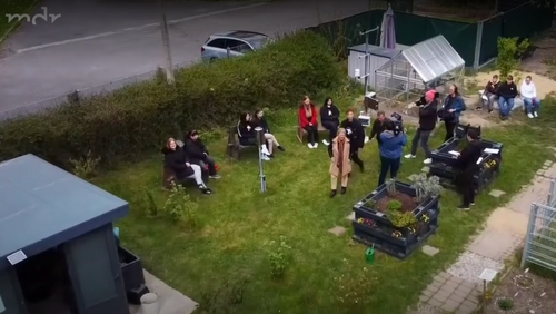 Vorschaubild: Luftaufnahme viele Personen, Schülerinnen und Schüler und Lehrkräfte im Schulgarten vor Gebäude und Gewächshaus, aus MDR: Klimadaten aus Leipziger Schulgarten, Video aus: "MDR Fernsehen MDR Garten 30.04.2023 08:30 Uhr"