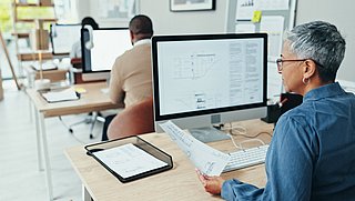 Foto, eine Frau arbeitet in einem Büro an einem Computer