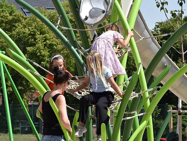 Foto, Kinder klettern auf einem grünen Klettergerüst auf einem Spielplatz im Freien an einem sonnigen Tag