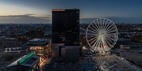Foto, Blick auf das Werksviertel Mitte in München bei Dämmerung, Gebäude und ein beleuchtetes Riesenrad