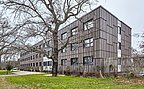 Foto, saniertes Verwaltungsgebäude mit grauer Holzfassade.