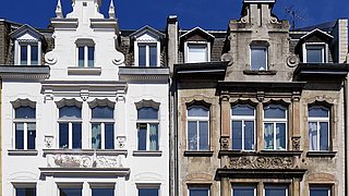 Foto, ein sanierter und ein unsanierter mehrstöckiger Altbau ähnlichen Typs nebeneinander.