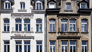 Foto, ein sanierter und ein unsanierter mehrstöckiger Altbau ähnlichen Typs nebeneinander.