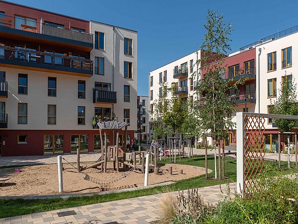 Foto, Kinderspielplatz vor modernen Mehrfamilienhäusern.