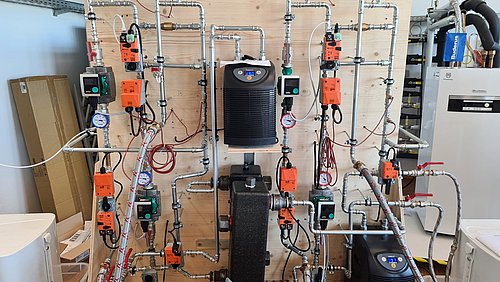Foto, Heizungstechnik (z.B. Rohre und Pumpen) montiert an einer Holzplatte.