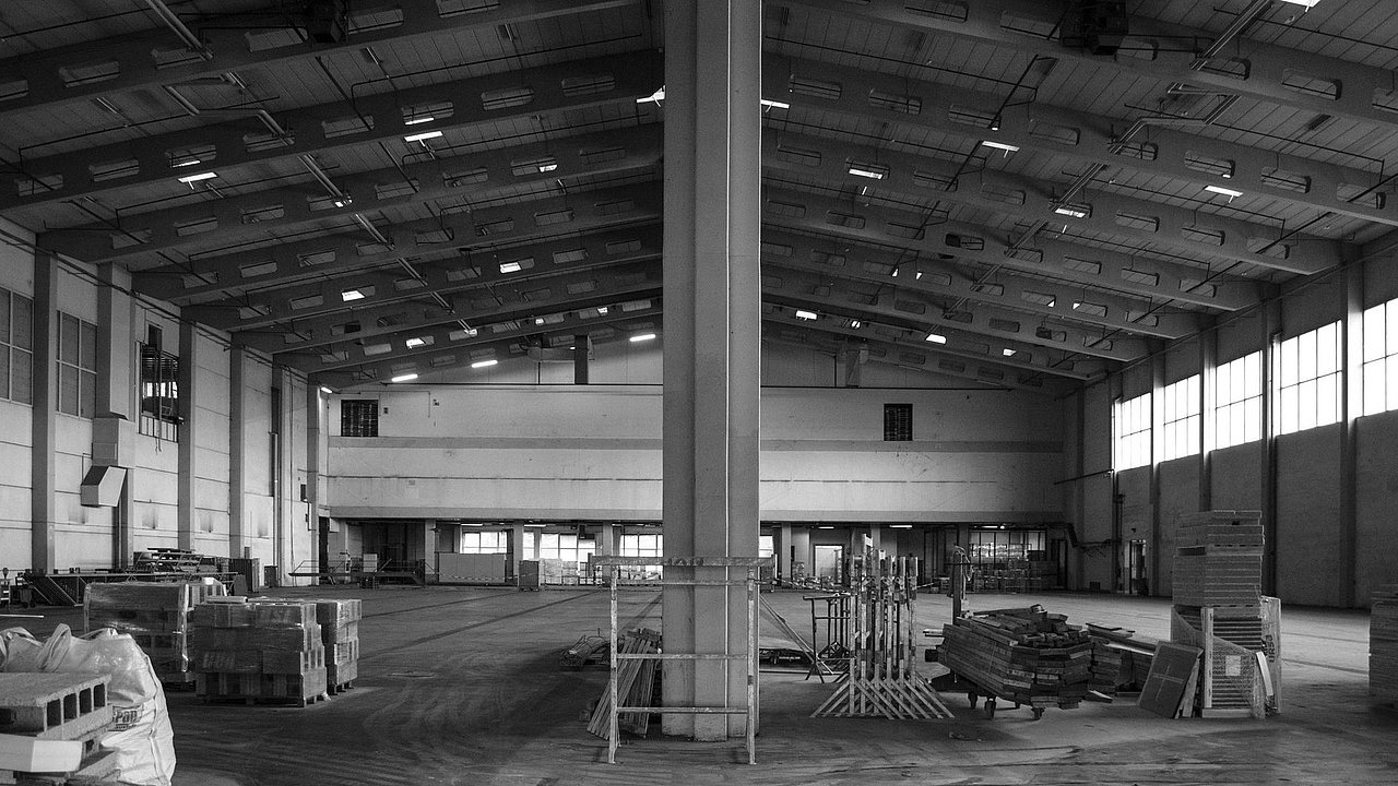 Foto, Große leere Lagerhalle mit hoher Decke, Baustoffen und Paletten