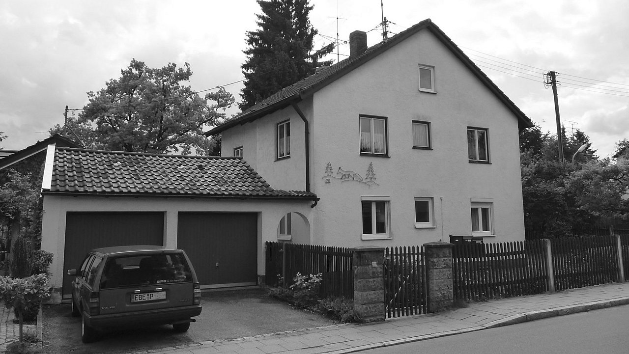 Foto, Zweistöckiges Wohnhaus mit Satteldach, angrenzender Garage und parkendem Auto vor dem Haus