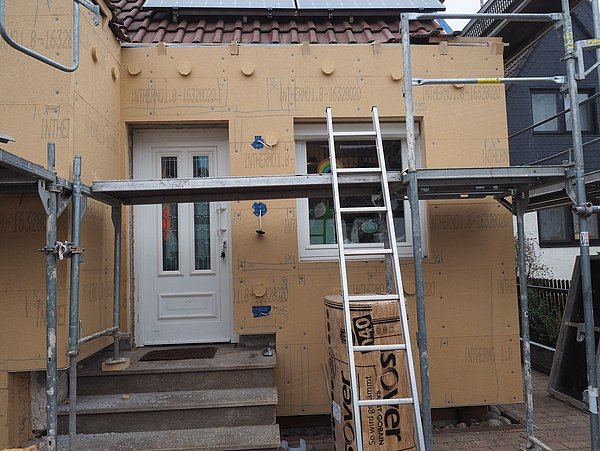 Foto, Außenfassade eines Einfamilienhaus, an der Dämmung angebracht wird. 