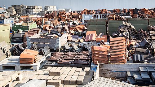 Foto, großes Lager mit gestapelten Dachziegeln und Baumaterialien auf Paletten im Freien