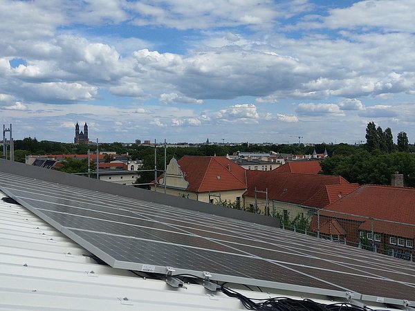 Foto, Solaranlage auf einem Dach mit Blick auf eine Stadtlandschaft und bewölktem Himmel