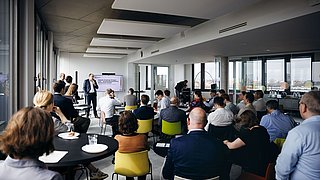 Foto, Präsentation in modernem Büro mit mehreren Zuhörern, Sprecher vor Bildschirm mit Text