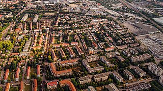 Foto, Luftaufnahme eines Wohngebiets mit mehreren mehrstöckigen Gebäuden, Straßen und Bäumen in einem städtischen Umfeld.