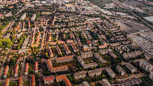 Foto, Luftaufnahme eines Wohngebiets mit mehreren mehrstöckigen Gebäuden, Straßen und Bäumen in einem städtischen Umfeld.