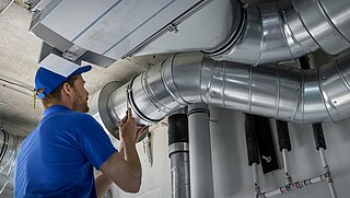 Foto, Lüftungstechniker arbeitet an einer an der Decke montierten Lüftungsanlage.